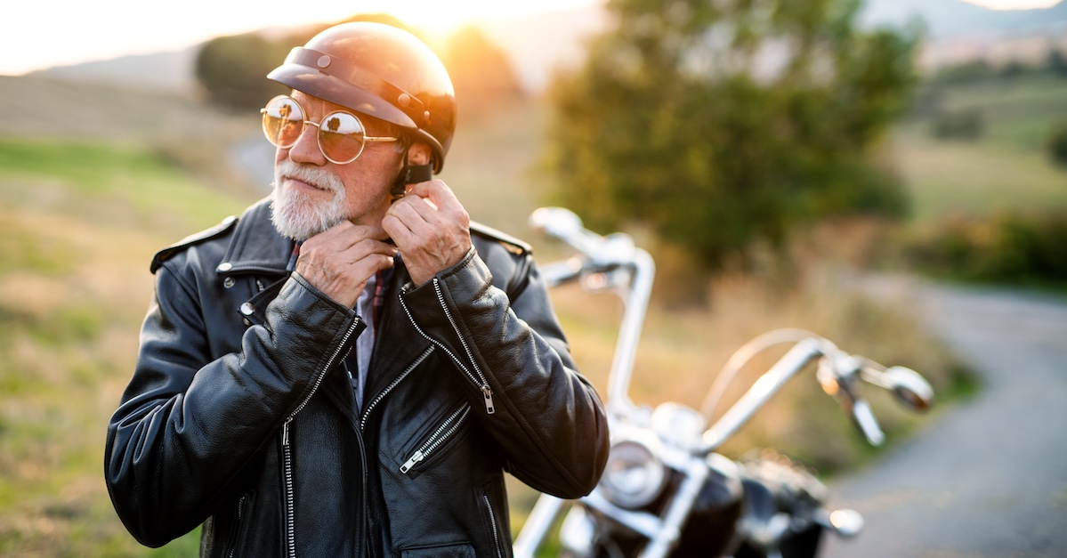 Older man putting on a helmet before riding his motorcycle